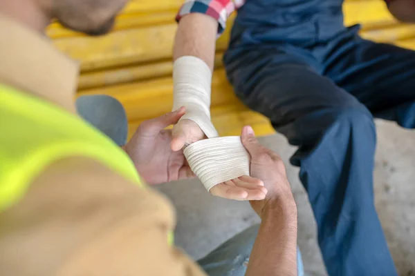 Close-up of building worker hands applying bandage on his coworker forearm — Stock Photo, Image