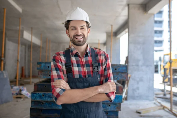 Obrero de la construcción con casco y camisa a cuadros de pie con los brazos cruzados —  Fotos de Stock