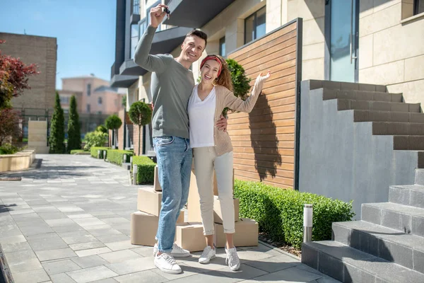 Hombre alto y su esposa de pie cerca de su nueva casa y sonriendo — Foto de Stock