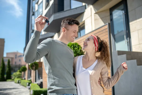 Hombre alto sosteniendo las llaves y su esposa sonriendo y abrazándolo — Foto de Stock