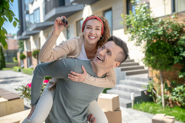 Smiling woman sitting on her husbands back and feeling excited