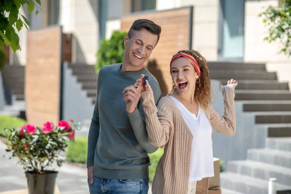 Feliz joven pareja sintiéndose increíble después de conseguir la llave de su nueva casa — Foto de Stock