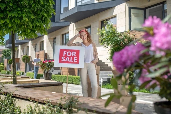 Smiling young woman standing with a table for sale — Stock Photo, Image