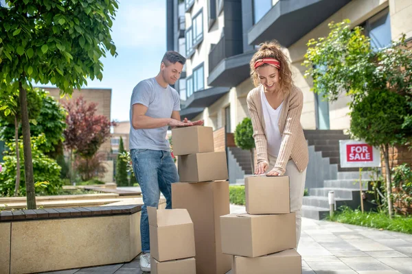 Pareja joven empacando cartulinas antes de mudarse a una nueva casa y buscando involucrado — Foto de Stock