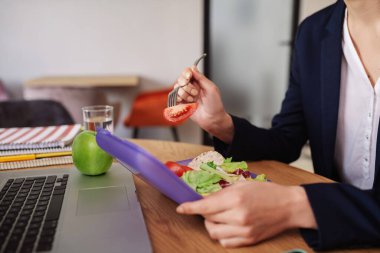 Domates dilimli çatal tutan kadın eller.