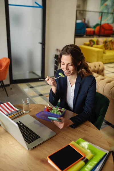 Comer menina com um smartphone no escritório — Fotografia de Stock