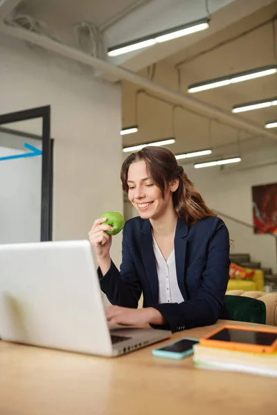 Souriante fille avec une pomme à un ordinateur portable — Photo