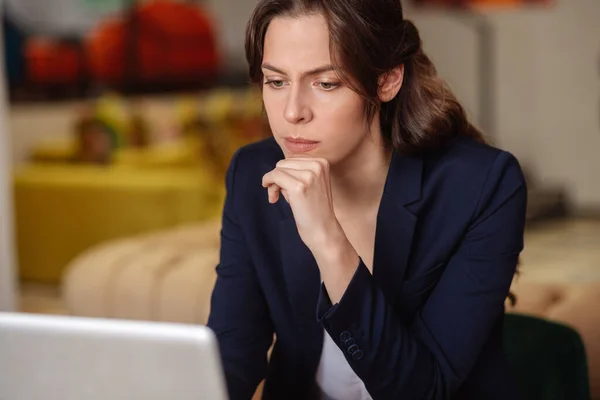 Long-haired serious girl working at a laptop. Stock Picture