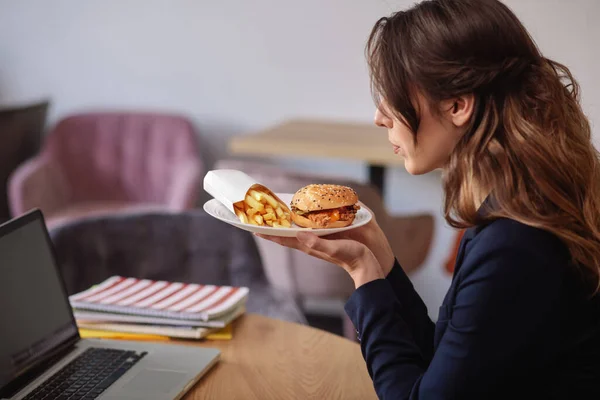 Woman in profile with plate of food in her hands