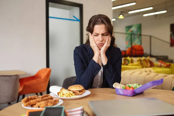 Jovem menina adulta com careta de descontentamento olhando para fast food — Fotografia de Stock