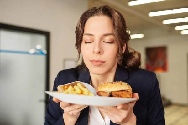 Contented face girl with closed eyes with plate of fast food. — Stock Photo, Image