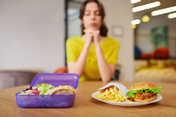 Ung kvinna sitter vid bordet och väljer mat. — Stockfoto