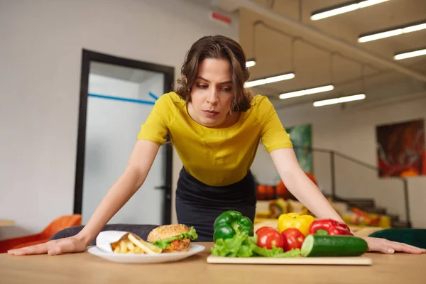 Långhårig kvinna i blus och kjol lutar sig över bordet med mat — Stockfoto