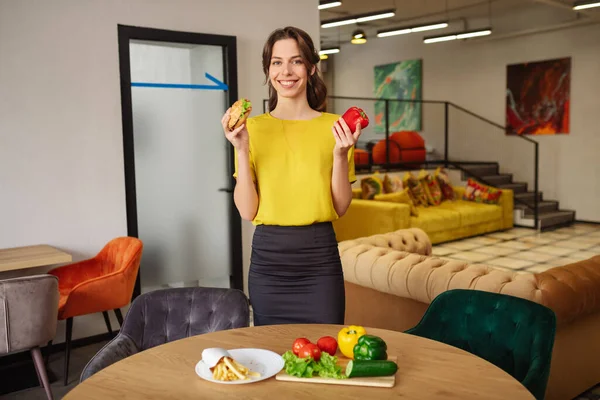 Mooie lachende vrouw met hamburger en rode peper. — Stockfoto