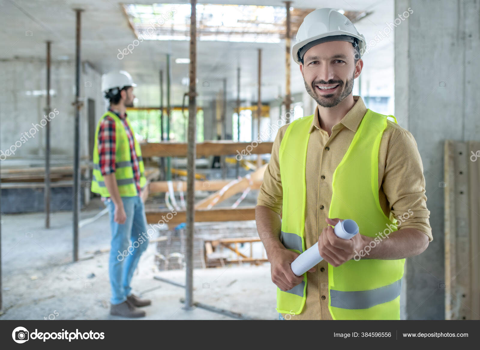 Bauarbeiter in gelber Weste mit Blaupause, lächelnd, sein Kollege
