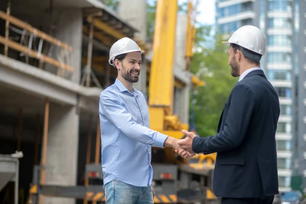 Épületvezető és művezető köszöntik egymást, kezet ráznak egymással az építkezésen. — Stock Fotó