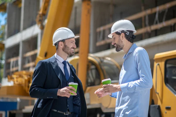 Supervisor del edificio y capataz bebiendo café, discutiendo algo, sonriendo — Foto de Stock