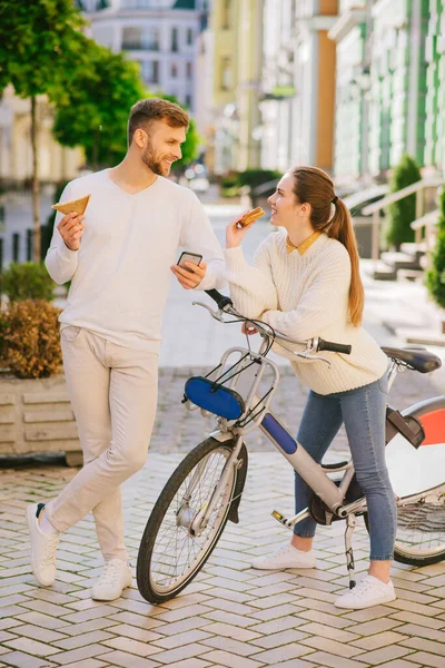 Мужчина со смартфоном и женщина с велосипедом стоят с бутербродами . — стоковое фото