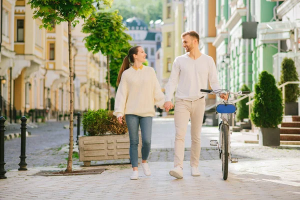 Homem com bicicleta e mulher segurando a mão olhando um para o outro — Fotografia de Stock