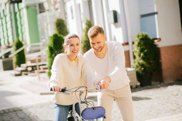 Mujer sonriente en bicicleta y un hombre asegurándola — Foto de Stock