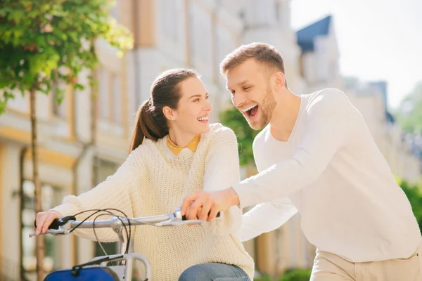 Man teaching a joyful woman riding bike — Stock Photo, Image