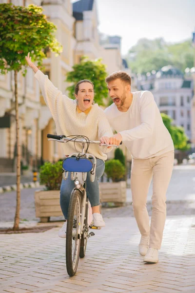 Mulher energética na bicicleta e homem nas proximidades na calçada — Fotografia de Stock