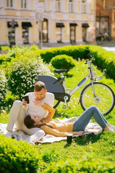 Genç adam ve kadın şehir bahçesinde piknikte oturuyor. — Stok fotoğraf