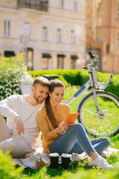 Concerned satisfied woman with tablet and man on grass — Stock Photo, Image