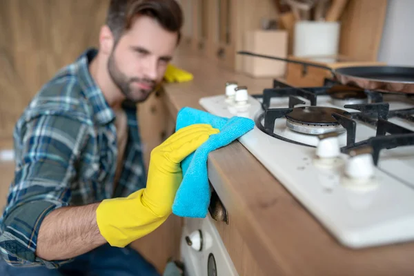 Mężczyzna w żółtych rękawiczkach czyści powierzchnię w kuchni — Zdjęcie stockowe