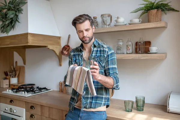 Junger Mann im karierten Hemd beim Gläserputzen — Stockfoto