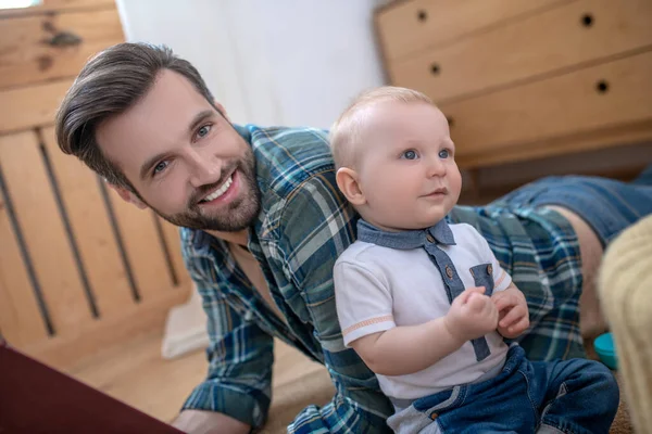 Tmavovlasý pohledný otec, usmívající se na svého syna na podlaze — Stock fotografie