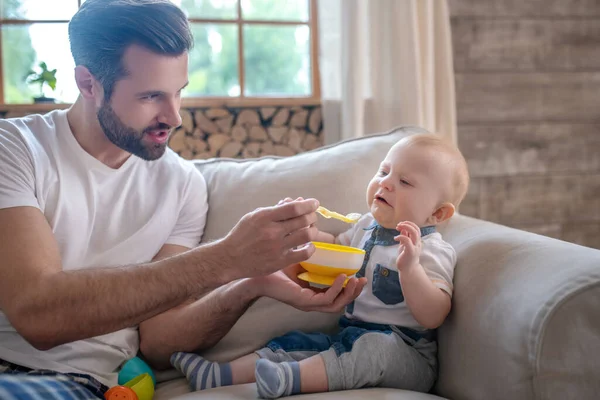 Junger Vater füttert das Baby und lächelt — Stockfoto