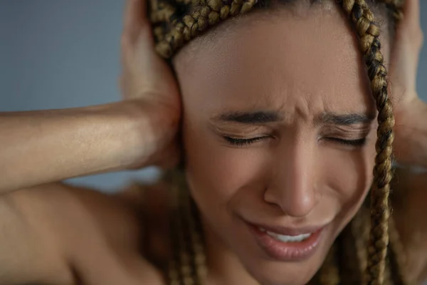 Απογοητευμένη νεαρή Αφροαμερικανή που υποφέρει, κατσουφιάζει, καλύπτει τα αυτιά της με τα χέρια της. — Φωτογραφία Αρχείου