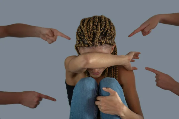 Triste jovem afro-americana sentada com os joelhos dobrados, cobrindo o rosto com uma mão — Fotografia de Stock