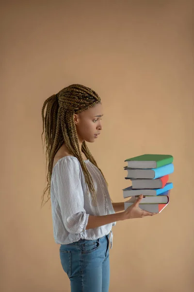Zklamaná mladá Afroameričanka s hromadou knih před sebou — Stock fotografie