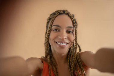 Gülümseyen genç Afrikalı Amerikalı kadın selfie yapıyor.