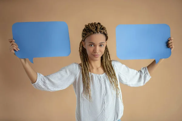 Lächelnde junge Afroamerikanerin erhebt zwei blaue Dialogwolken über ihrem Kopf — Stockfoto