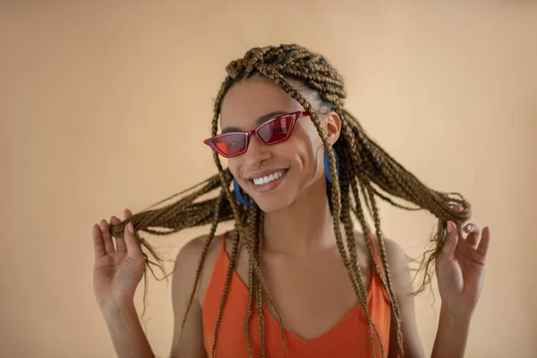 Smiling young African American playing with her dreadlocks — Stock Photo, Image