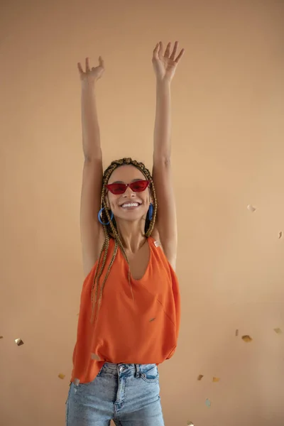 Улыбаясь, юная афроамериканка поднимает руки над головой под блестками. — стоковое фото