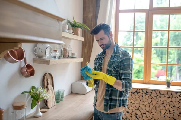 Hombre de pelo oscuro con camisa a cuadros y guantes amarillos en la cocina — Foto de Stock