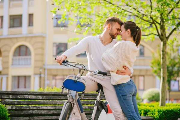 Młody szczęśliwy przytulanie mężczyzna na rowerze i kobieta stoi w pobliżu — Zdjęcie stockowe