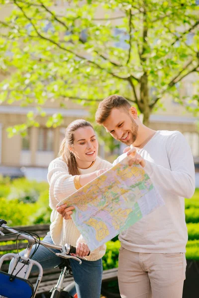 Hombre y una mujer con bicicleta examinando cuidadosamente el mapa — Foto de Stock