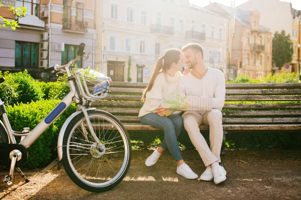 Loving man and woman with map on bench near bicycle — Stock Photo, Image