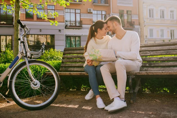 Woman and man with map sitting on bench touching faces — Stock Photo, Image