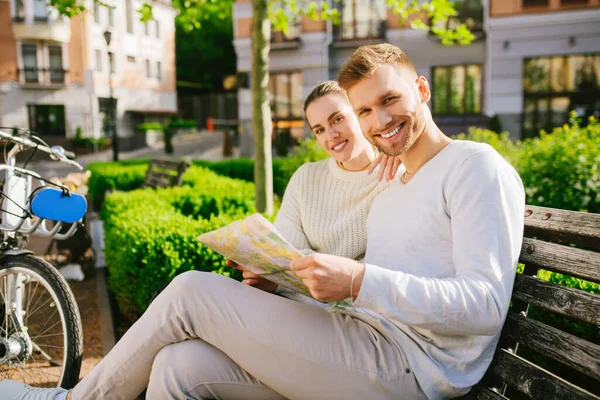 Joyful young man and woman with map on bench — Stock Photo, Image