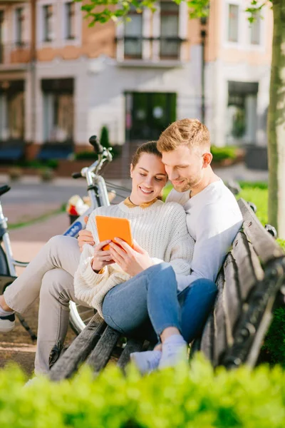Young man and woman resting on bench with atablet — Stock Photo, Image