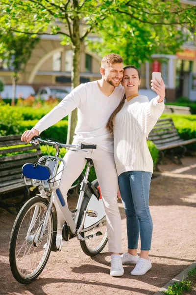 Mężczyzna na rowerze i kobieta ze smartfonem stojącym na chodniku — Zdjęcie stockowe