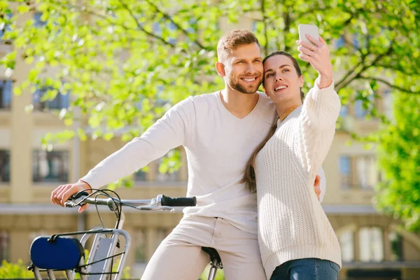 Hombre feliz en bicicleta y mujer con teléfono inteligente en la mano extendida . — Foto de Stock