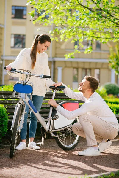 Frau stützt Fahrrad und Mann duckt sich — Stockfoto
