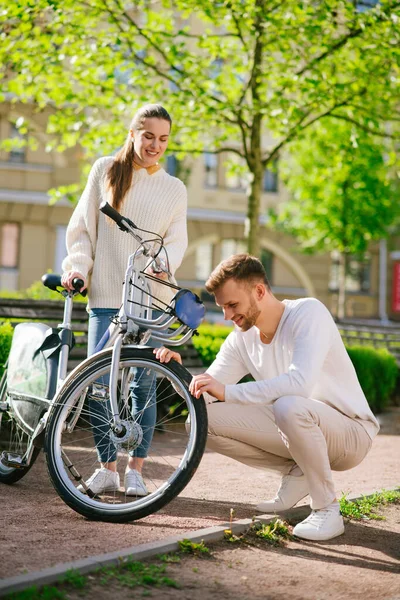 Mulher com bicicleta e homem olhando roda — Fotografia de Stock